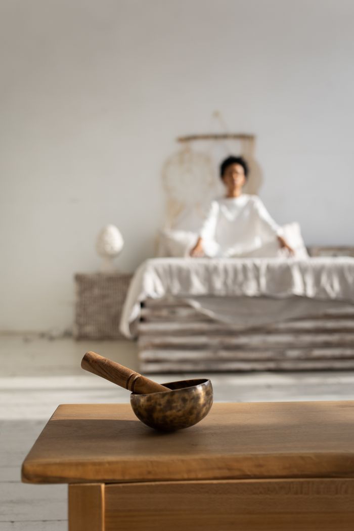 A serene indoor scene featuring a woman practicing yoga with a singing bowl, promoting mindfulness and relaxation.